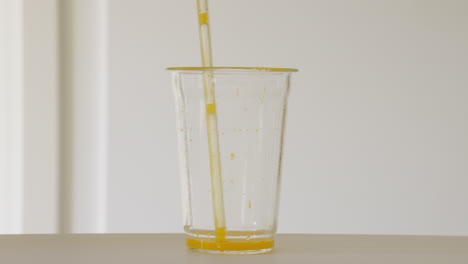 Refreshing-orange-juice-in-glass-quickly-sucked-through-glass-straw