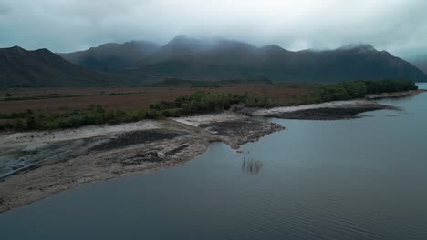 Drone-view-of-landscape-of-mountain-range-in-Tasmania-with-Lake-Burbury-in-foreground-in-Australia