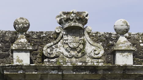 Detailed-pan-across-weathered-moss-lichen-covered-stone-structures-at-top-of-church-building