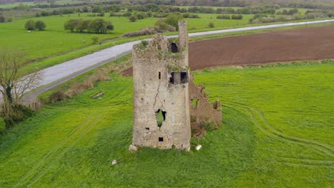 Srah-Castle-along-canal-banks-in-open-grassy-field-on-windy-day,-aerial-orbit