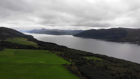 Aerial-View-Over-Green-Valley-River-Bank-Trees-With-Loch-Ness-In-The-Scottish-Highlands
