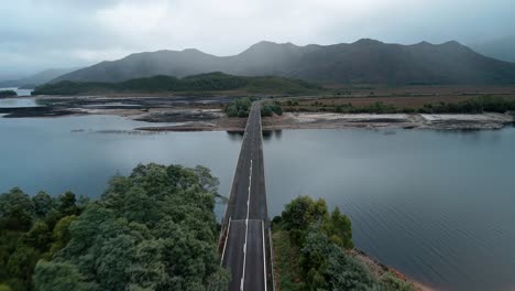 Forward-drone-view-of-an-empty-bridge-with-beautiful-skyscape-and-landscape-of-mountains-in-Tasmania,-Australia