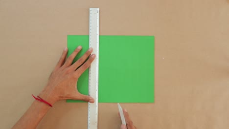 Marking-folds-on-green-paper-with-the-ruler-and-bone,-paper-crafts