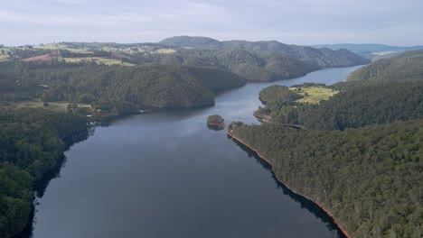 Wide-aerial-view-of-Lake-Barrington-with-hills-and-bush-forest-near-Sheffield-in-Tasmania,-Australia