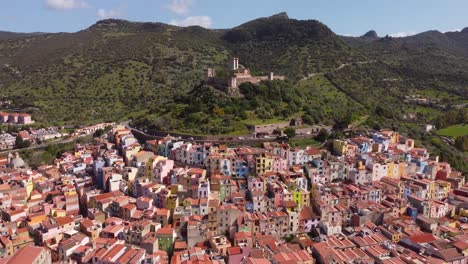 Imágenes-De-Drones-Muestran-La-Encantadora-Ciudad-De-Bosa,-Cerdeña,-Con-Su-Bosque-Circundante-Y-Su-Castillo-Histórico,-Una-Perspectiva-Cautivadora-Para-Metrajes-De-Archivo