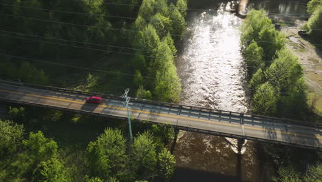 Sunlight-glistens-on-Wolf-River-with-a-car-crossing-the-bridge-in-Collierville,-Tennessee,-aerial-shot