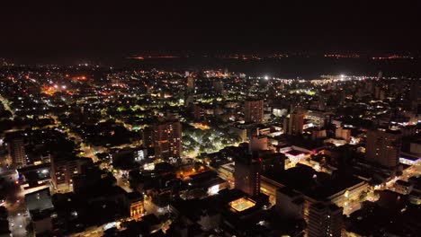 Drone-flight-over-the-center-of-the-city-of-Posadas,-passing-near-the-buildings-with-the-lights-on