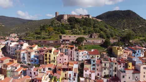 Experimente-El-Viaje-Desde-La-Ciudad-De-Bosa,-Cerdeña,-Hasta-Su-Majestuoso-Castillo-Ubicado-Entre-Montañas-Y-Bosques-En-Cautivadoras-Imágenes-Tomadas-Con-Drones,-Perfectas-Para-Imágenes-De-Archivo.