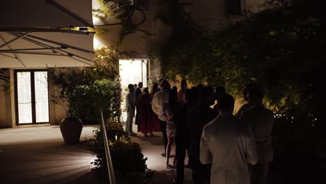 Slow-motion-shot-of-wedding-guests-waititng-to-enter-the-villa-at-night