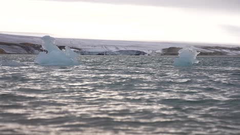 Trozos-De-Hielo-En-Agua-De-Mar-Fría-Bajo-La-Costa-Y-El-Glaciar,-Cámara-Lenta