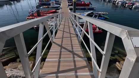 Rampa-De-Acceso-Al-Muelle-Del-Puerto-Deportivo-Con-Embarcaciones-De-Recreo-De-Pie-Con-El-Mar-En-Calma-En-Un-Día-De-Verano-Antes-De-La-Llegada-De-Los-Turistas,-Revelador-Disparo-Hacia-Arriba