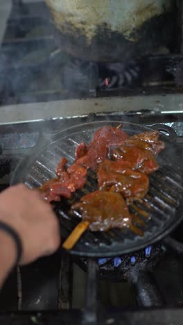 Juicy-kidney-meat-on-sticks-cooking-on-hot-grill-in-restaurant,-sparkling-flames,-vertical-close-up