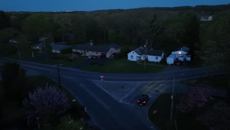 Black-car-at-intersection-not-stopping-at-stop-sign-on-street-in-American-suburb