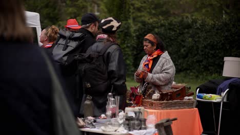 Mujer-Holandesa-De-Color-Vendiendo-Artículos-Para-La-Venta-Durante-El-Mercadillo-De-Koningsday