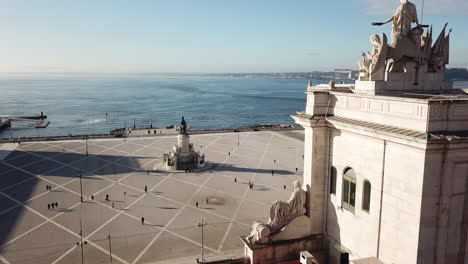 Lisbon,-Commercial-Square-drone-footage-starting-behind-the-Rua-Agusta-Arc-toward-to-the-Tejo-river-passing-by-the-King-Jose-Statue-on-a-sunny-day-with-blue-skies