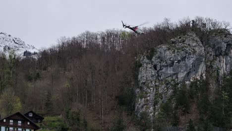 Helicopter-hoisting-supplies-over-snow-capped-Weesen-mountains,-Switzerland