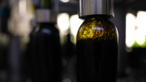 Green-glass-bottles-filling-with-red-wine-at-a-production-line-in-Vignonet-France,-Close-up-shot