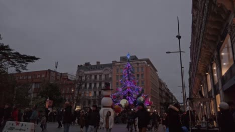 A-shot-of-a-square-with-a-giant-moving-christmas-tree-illuminated