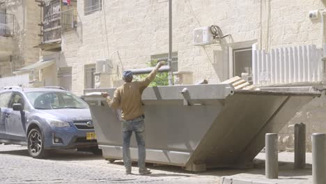 A-man-throwing-pipes-into-a-dumpster