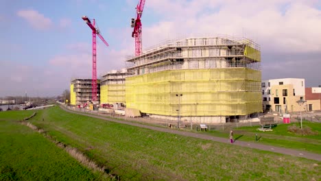 Panorama-Del-Atardecer-De-Grullas-Rojas-Que-Se-Elevan-Sobre-El-Sitio-De-Construcción-Noorderhaven-Parte-Del-Desarrollo-Urbano-Y-El-Barrio-De-Viviendas-Visto-Desde-Las-Llanuras-Aluviales-Del-Río-Ijssel