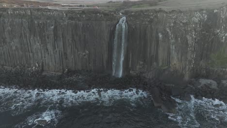 Slow-arcing-shot-of-the-Basalt-cliffs-with-the-Mealt-Falls-flowing-at-sunset