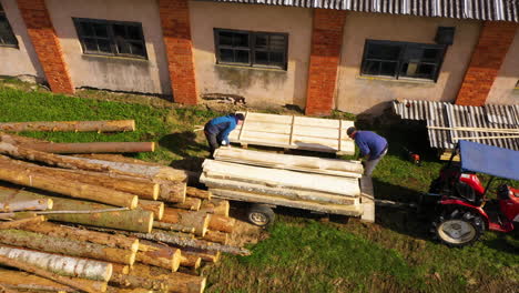 Manual-labor-of-stacking-wooden-boards-in-a-pile-for-drying-in-sunlight-outside