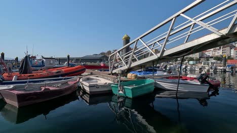 Maritime-rescue-boat-stops-at-the-port-in-the-middle-of-the-local-fishing-boats-with-the-buildings-behind-and-the-ramp-going-down-to-the-boardwalk,-revealing-plane