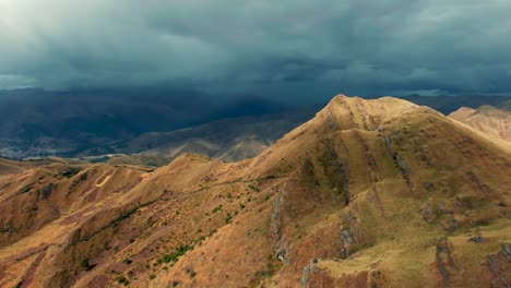 Andean-golden-landscape-unveils-ancient-Huanacaure-ruins-amidst-majestic-valleys-near-Cusco,-Peru,-under-a-deep-blue-cloudy-skyline