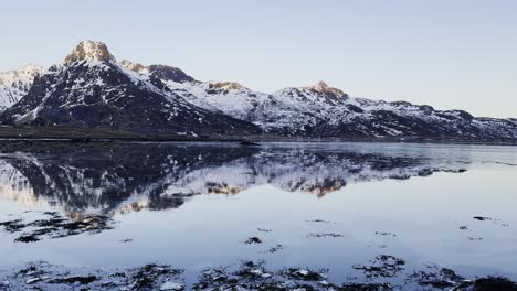 Mountain-reflection-on-calm-water-in-Lofoten,-Norway-during-twilight,-serene-landscape,-wide-shot