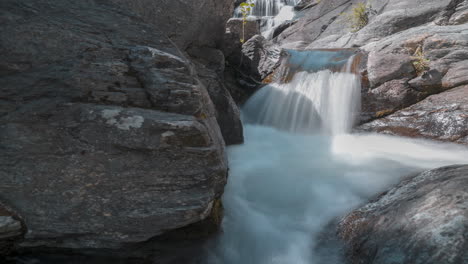 Arroyo-De-Montaña-Cayendo-En-Cascada-Sobre-Rocas,-Una-Cascada-Serena-En-Un-Entorno-Natural,-Capturada-En-Un-Timelapse-Fluido