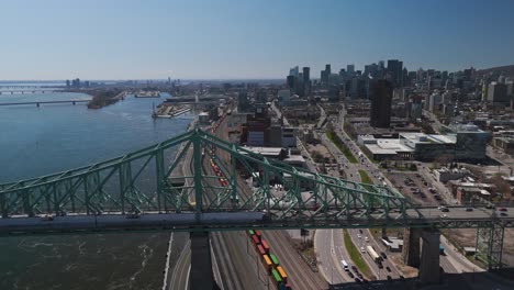 drone-footage-of-The-Jacques-Cartier-Bridge-traffic-car-crossing-the-Saint-Lawrence-River-from-Montreal-Island,-revealing-the-skyline-cityscape-,-Canada
