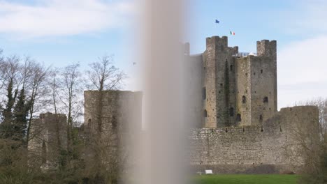 Castillo-Medieval-En-El-Condado-De-Meath,-Irlanda,-Con-Banderas-Ondeando,-Vista-Parcial-A-Través-De-Un-Primer-Plano-Borroso