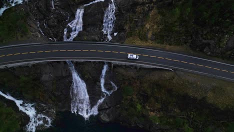 Vista-De-Arriba-Hacia-Abajo-De-La-Minivan-Cruzando-El-Puente-Sobre-La-Cascada-Langfossen,-Noruega