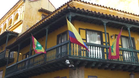 Cartagena-and-Colombia-waving-flags-against-a-backdrop-of-historic-architecture,-heritage-and-national-pride