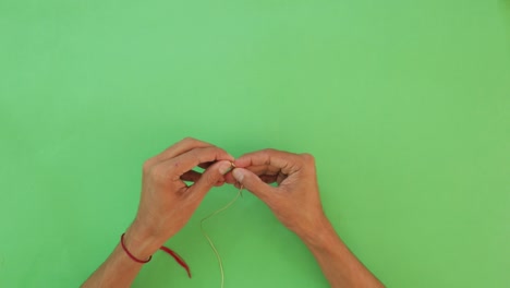 Needlework-Focus.-Male-Threading-Thread-on-Green-Table