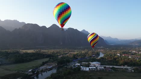drone-shot-of-colorful-hot-air-balloons-in-Vang-Vieng,-the-adventure-capital-of-Laos