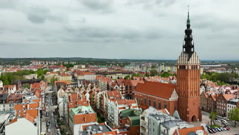 Aerial-view-of-the-historic-Elbląg-Cathedral-towering-over-the-old-town,-with-a-tapestry-of-terracotta-roofs-extending-into-the-modern-cityscape