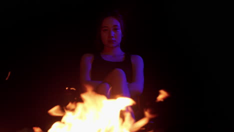 asiatic-woman-young-girl-sitting-in-front-of-bonfire-fire-while-sitting-in-camping-chair