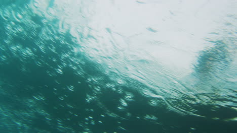 Rearview-of-wave-as-surfer-rides-and-barrel-closes-out-into-white-wash-above-reef