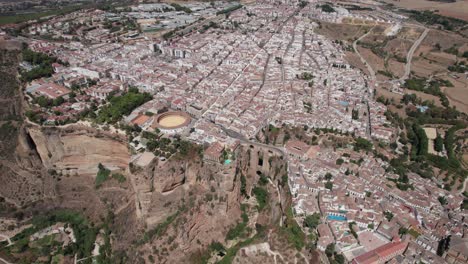 aerial-circle-pan-shot-of-bullring-and-el-Tajo-gorge-bridge-in-Ronda,-Andalusia-Spain