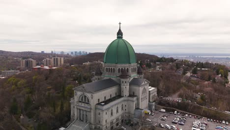 drone-approach-Saint-Joseph's-Oratory-of-Mount-Royal,-Montreal-Roman-Catholic-minor-basilica-Quebec-Canada-aerial-footage-cityscape-at-distance