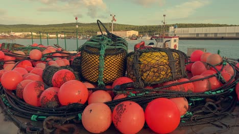 Bright-red-buoys-embellish-the-docks-of-a-scenic-Spanish-fishing-village,-firmly-attached-to-the-coastal-jetty,-providing-a-glimpse-into-the-charm-of-this-cozy-harbor-and-its-fishing-community