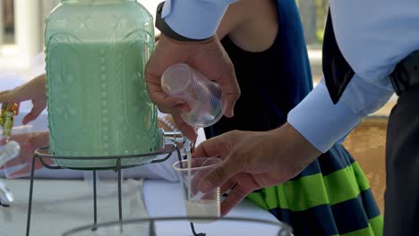 Pouring-drink-from-a-decorative-dispenser-into-a-clear-cup