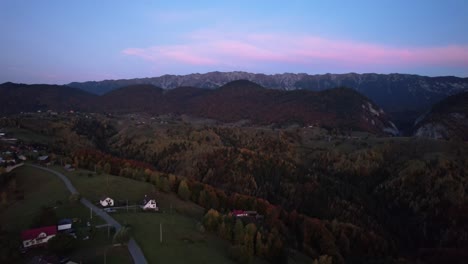 Magura-village-at-dusk-with-piatra-craiului-mountains-backdrop,-autumn-colors,-aerial-view