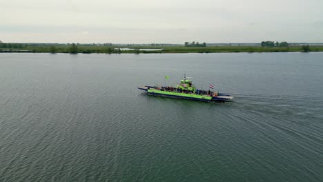 Ferry-sails-in-the-middle-of-the-river-drone-circles-sideways-with-the-ferry,-flag-at-half-mast-in-connection-with-Remembrance-Day