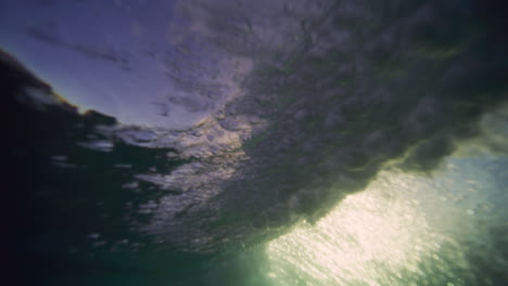 View-of-glowing-blue-golden-green-light-across-underwater-breaking-wave