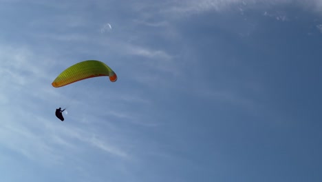 A-paraglider-pilot-gracefully-soars-against-the-backdrop-of-the-azure-sky,-embodying-the-freedom-of-flight-amidst-boundless-horizons