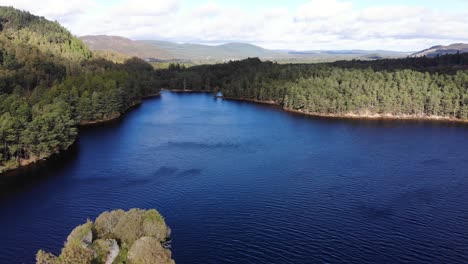 Aerial-View-Of-Dark-Blue-Loch-an-Eilein-Surrounded-By-Pines-Of-Rothiemurchus-Forest