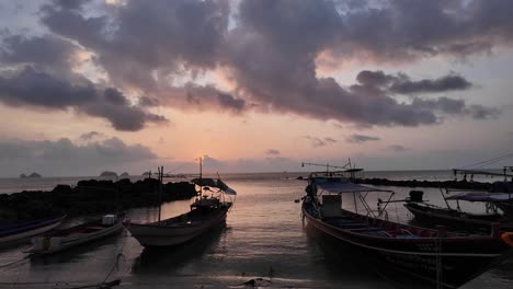 Fishing-boats-at-sunset-on-Koh-Samui,-silhouetted-against-a-vibrant-sky,-calm-sea,-tranquil-evening