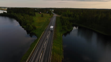 RV-driving-over-a-bridge-in-middle-of-the-arctic-countryside-of-Lapland---Aerial-view